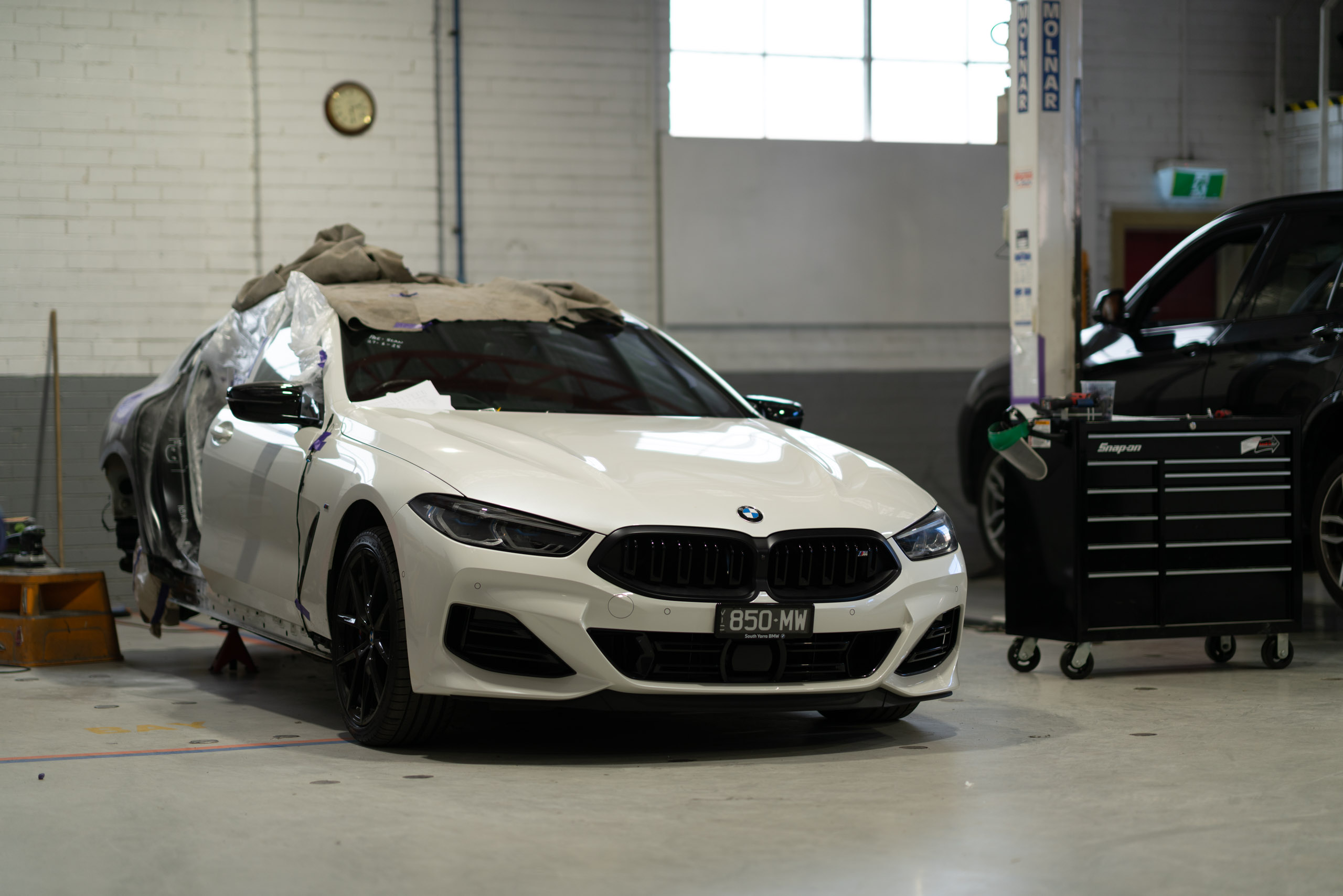 White BMW 8 Series masked for paint refinishing in the workshop