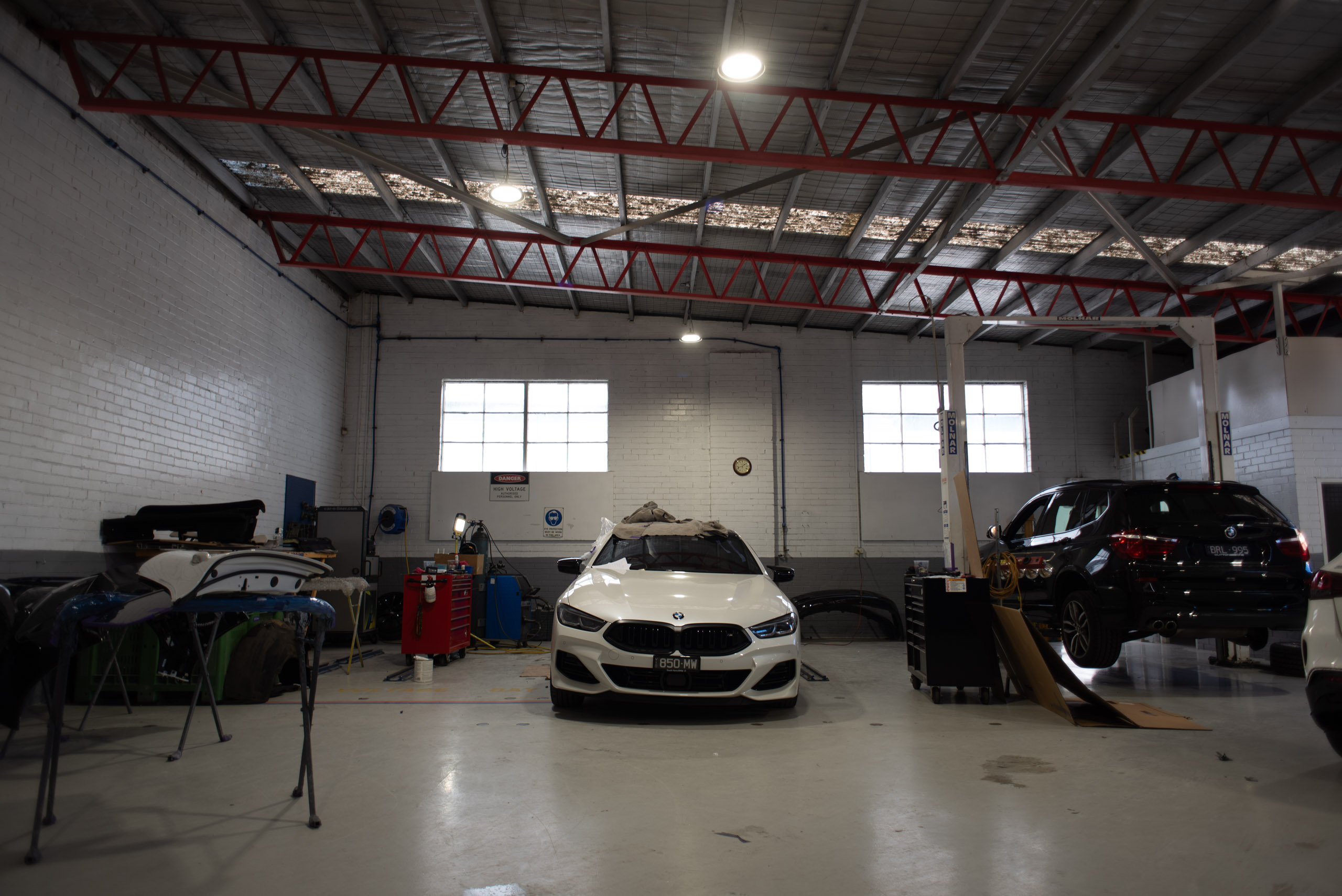 Repair workshop with a white BMW 8 Series and panels prepared for repair