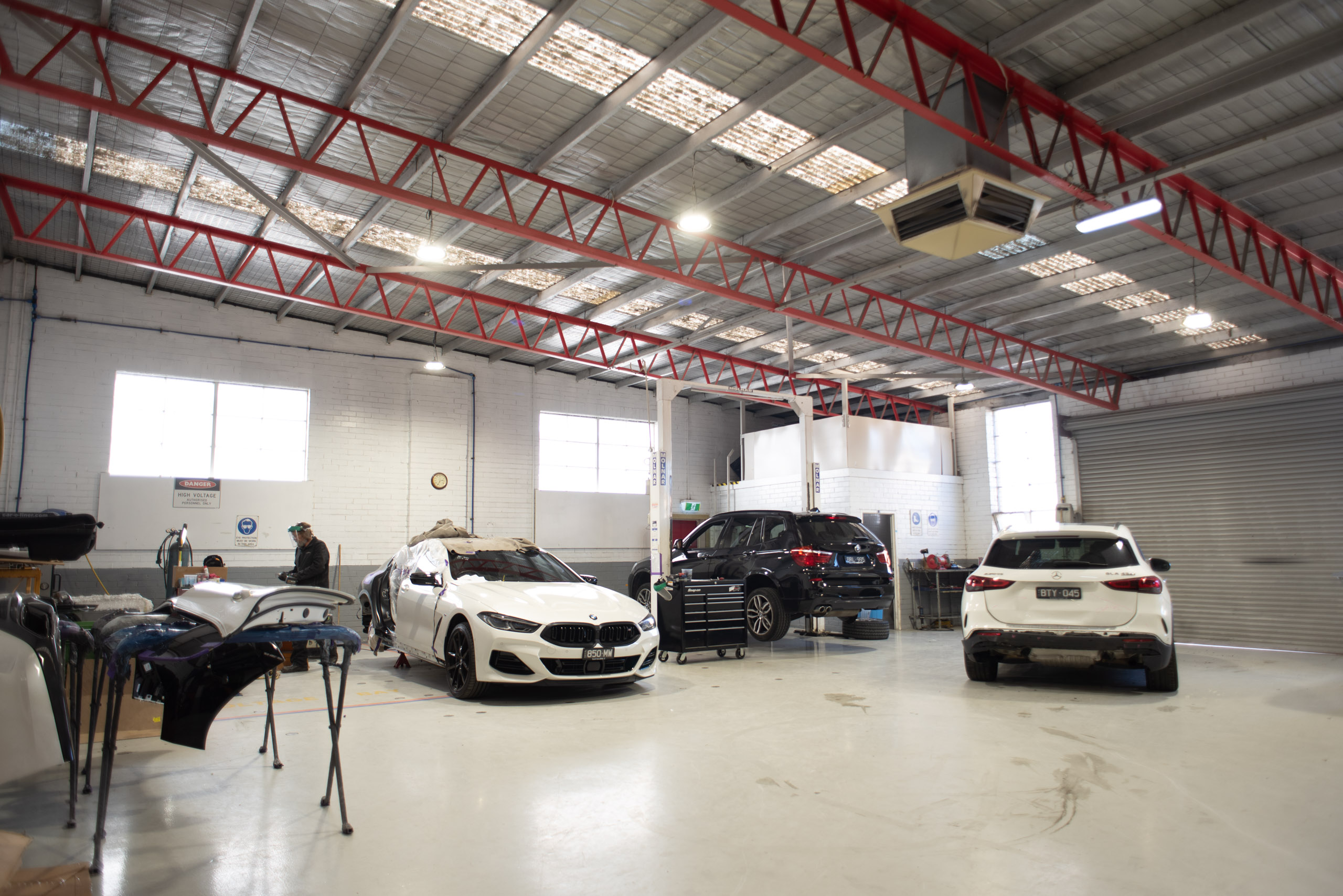 Repair workshop with bumper covers on stands and prestige vehicles in for repair